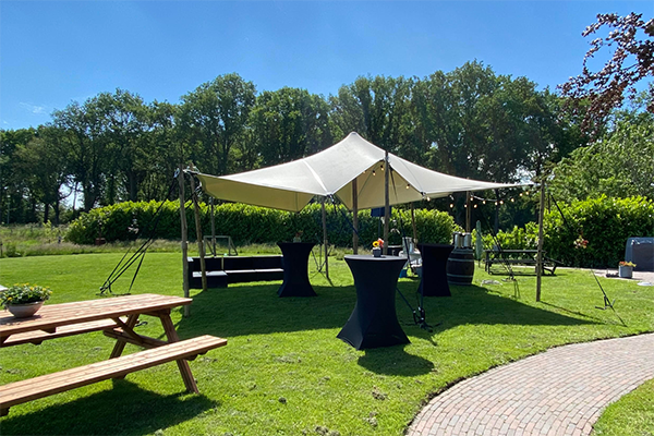A stretch tent on a sunny day, setup for an event.
